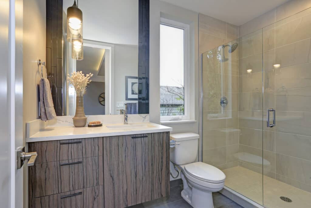 New luxury bathroom in grey tones offers glass shower and single bathroom cabinet.